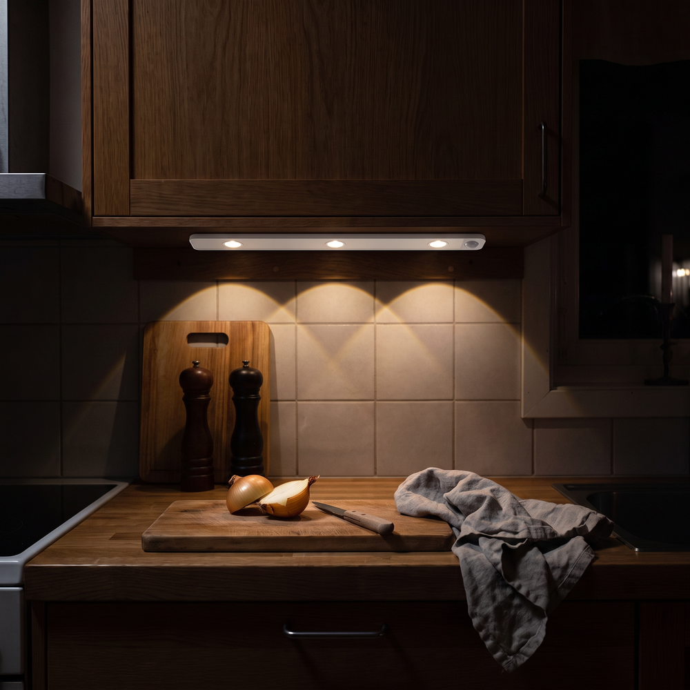 The same worktop with Lyra fitted under the wall cupboard and switched on, warm arcs of light over the chopping board
